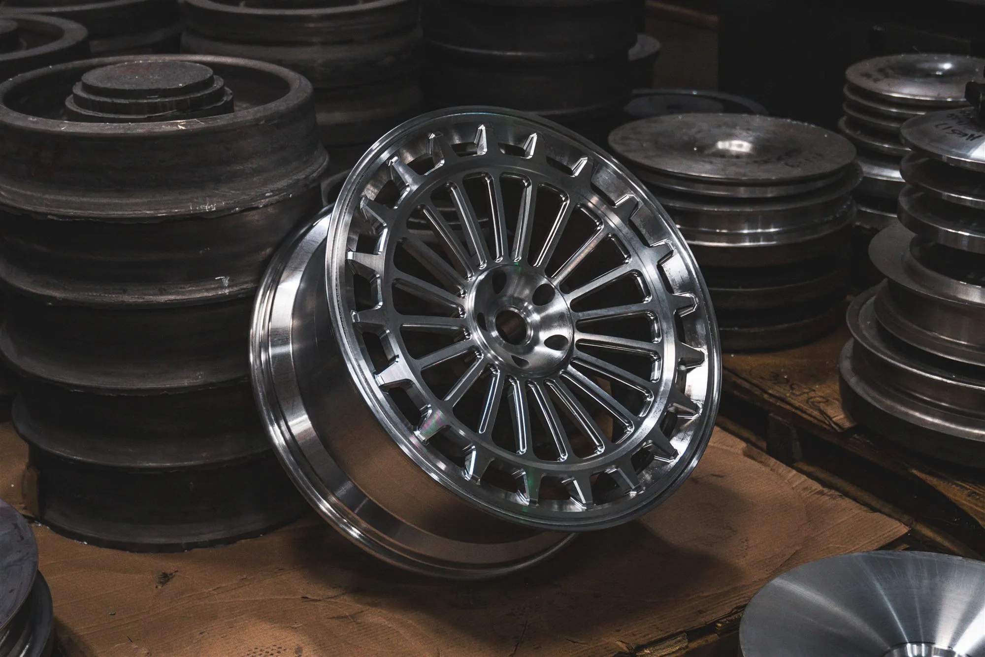 Freshly machined forged wheel among raw forging blanks in the Avant Garde machine shop